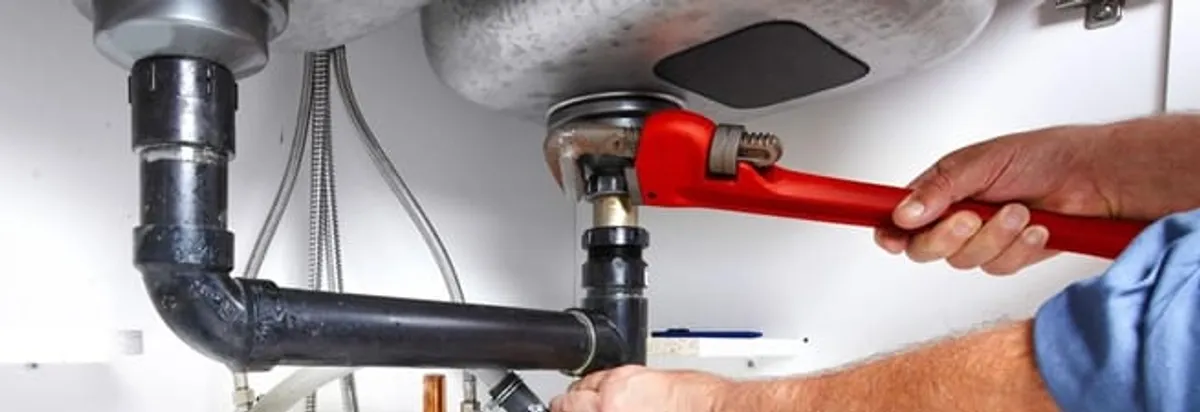 Garbage disposal repair technician tightening the sink drain and disposal connection in Charlotte, NC