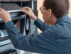 Appliance repair technician replacing a microwave vent filter in Charlotte, NC