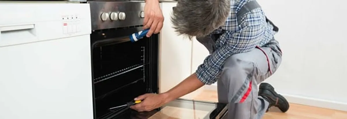 Oven repair technician inspecting and servicing an electric oven in Charlotte, NC