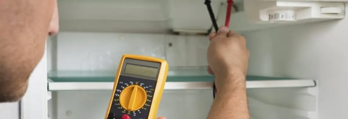 Refrigerator repair technician testing electrical components with a multimeter in Charlotte, NC