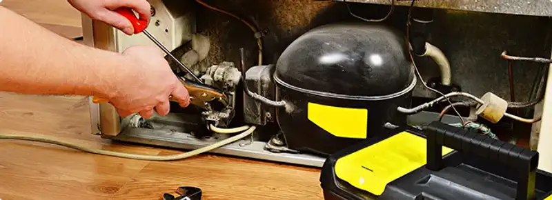 Refrigerator repair technician fixing the compressor and wiring in Charlotte, NC