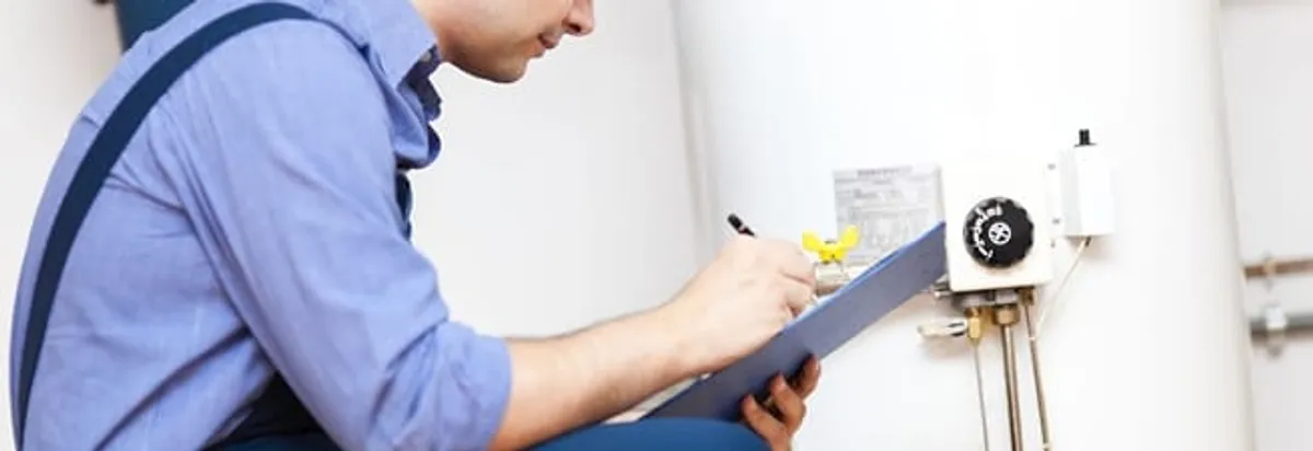 Water heater repair technician inspecting the unit and recording service notes in Charlotte, NC